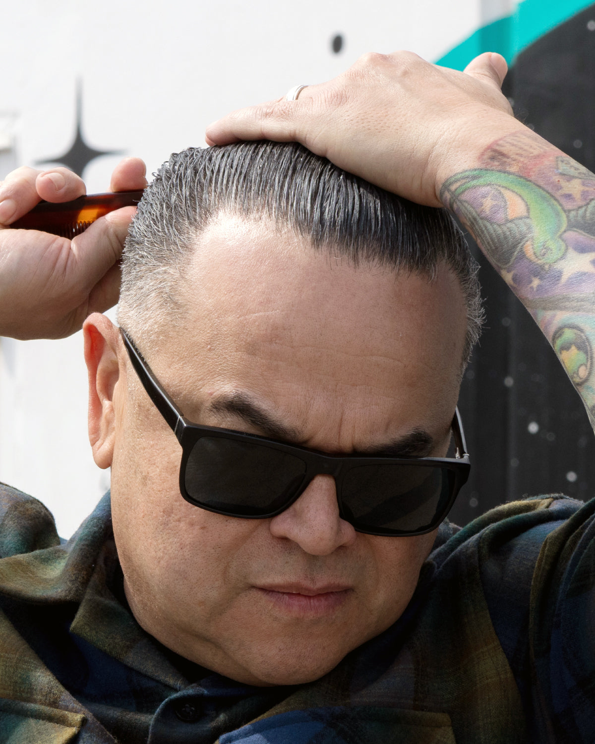 Person styling hair with sunglasses on